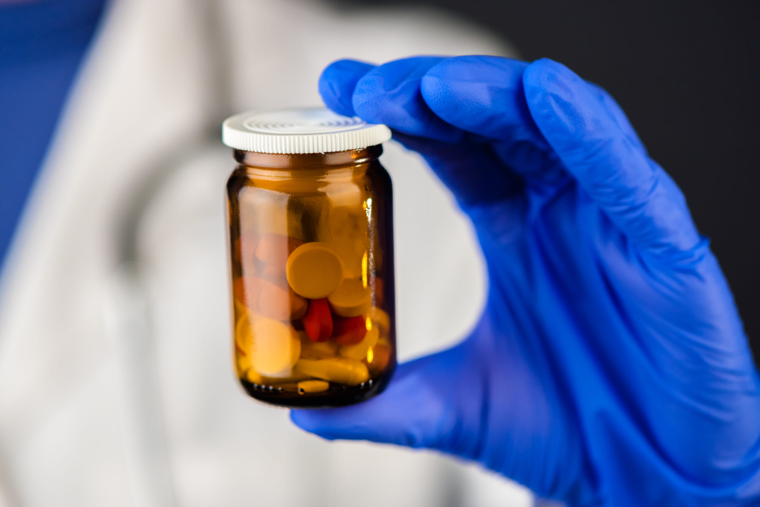 Female doctor holding unlabeled bottle of various pills and medi